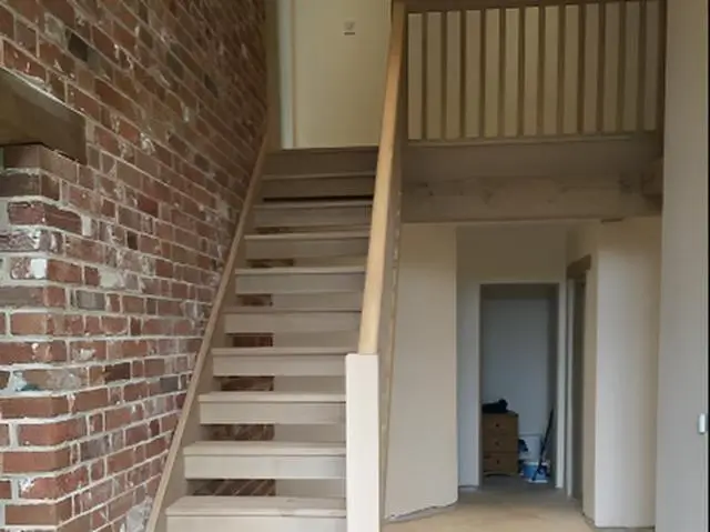 Oak staircase under construction beside a brick wall